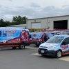 Multiple wrapped vans parked outside a warehouse for a Fredericksburg HVAC company, featuring cohesive red, white, and blue designs created by Core Prints.