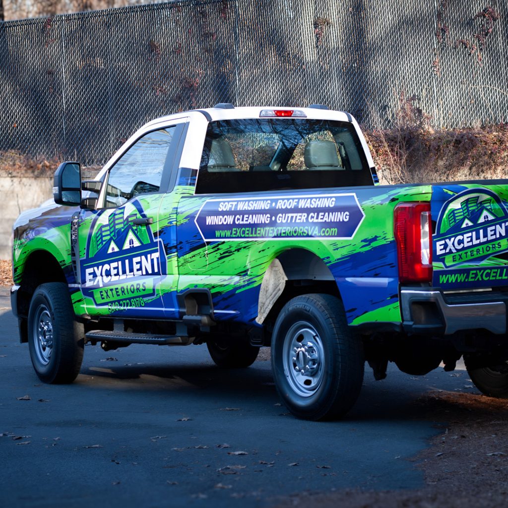 Truck wrap for Excellent Exteriors featuring bright blue and green branding and service listings for roof washing, window cleaning, and gutter cleaning.